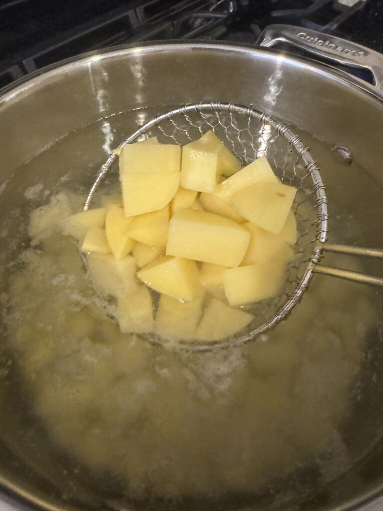 cooked potatoes in large pot of water on spider strainer