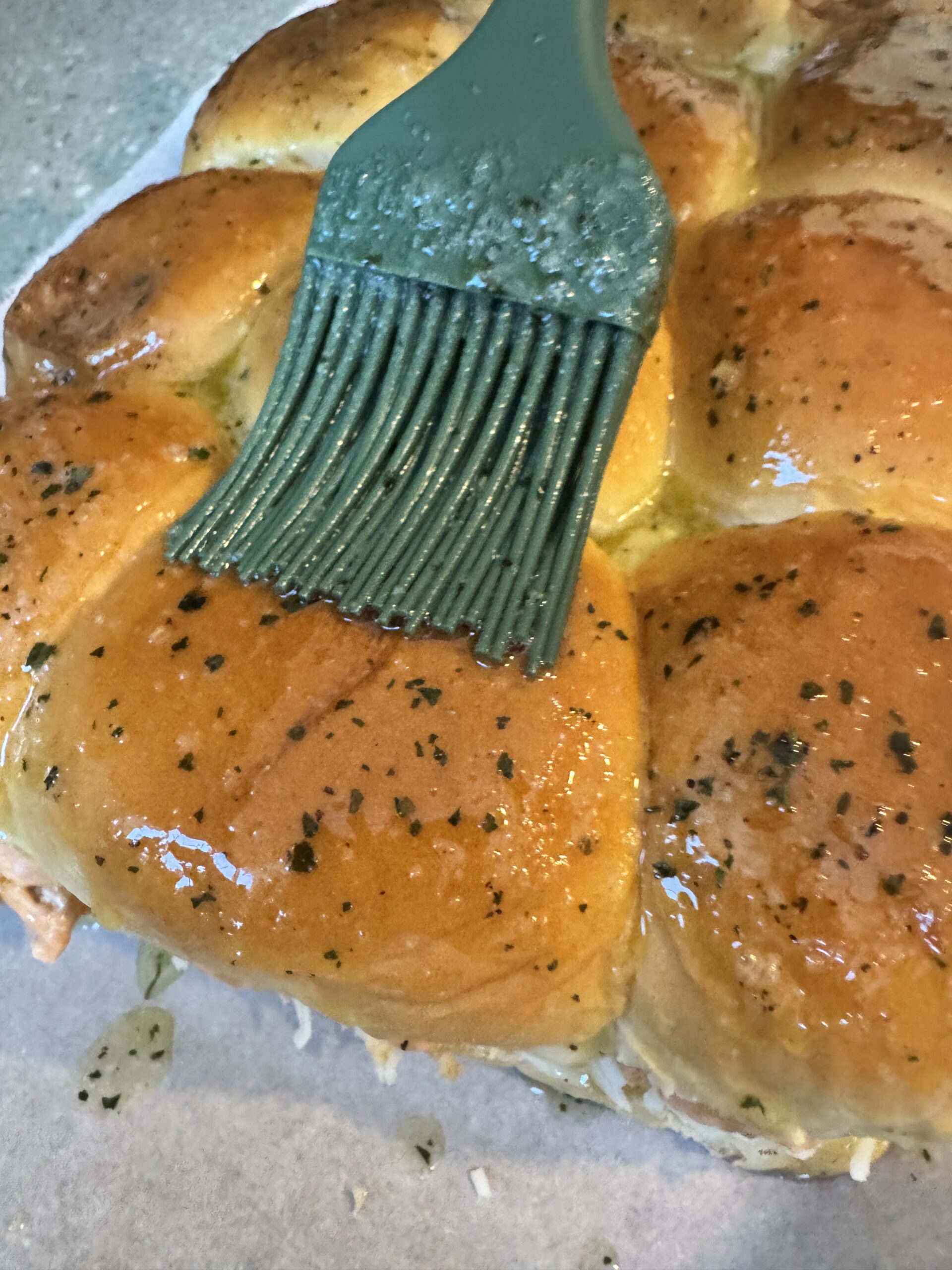 butter and ranch powder being lathered onto buffalo chicken sliders 