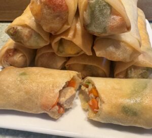 plated eggrolls with one cut in half showing the chicken and vegetable filling