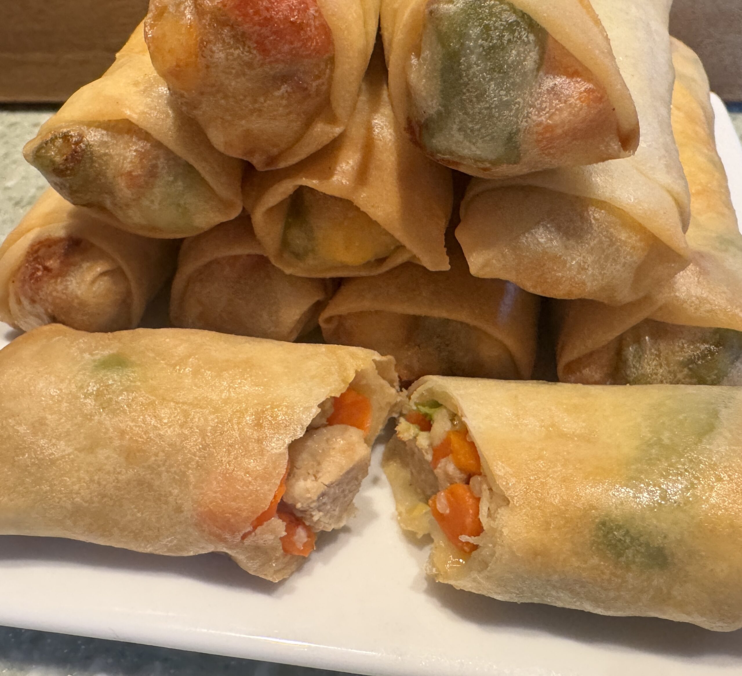 plated eggrolls with one cut in half showing the chicken and vegetable filling