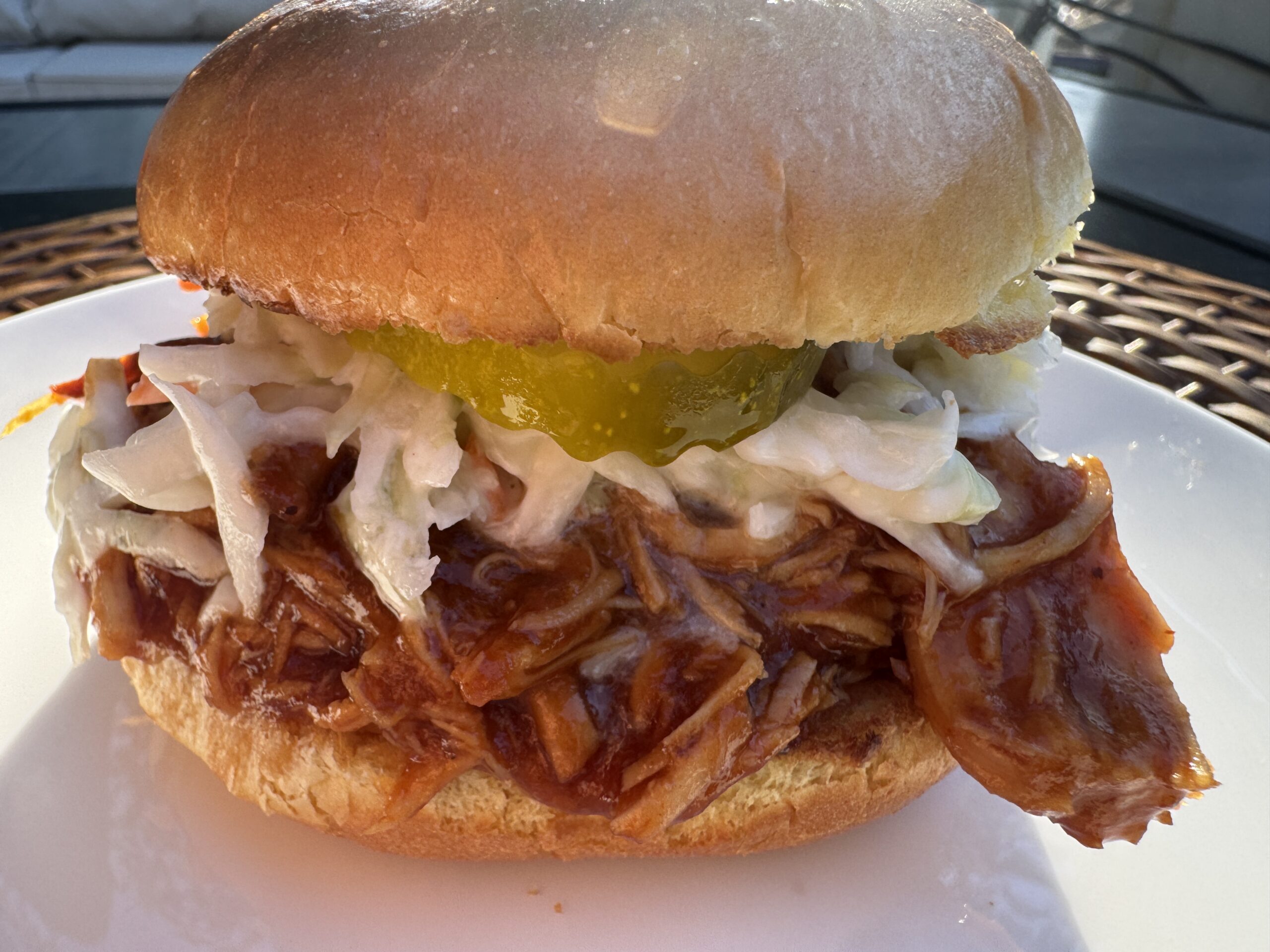 Bbq pulled chicken sandwich in a brioche bun with pickles and coleslaw